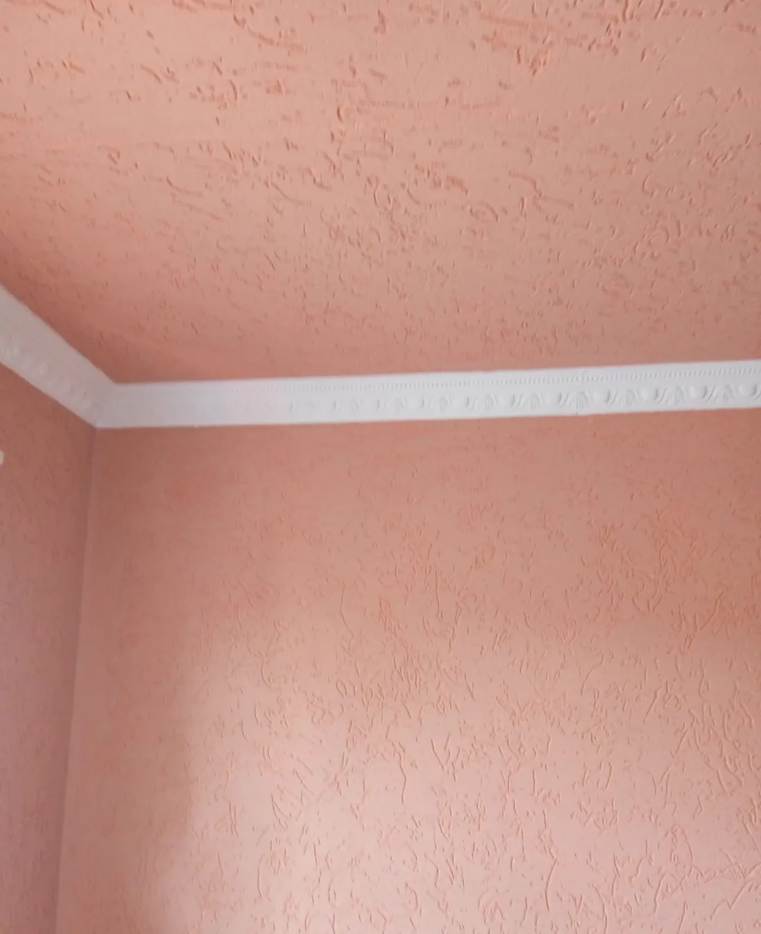 Decorative white cornice moulding installed on a textured wall