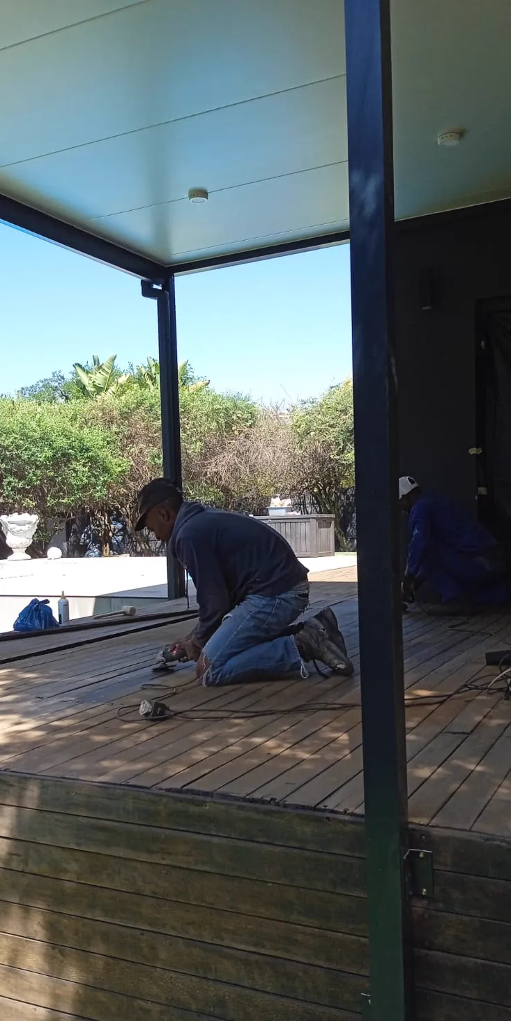 Covered patio deck under construction beside a pool area