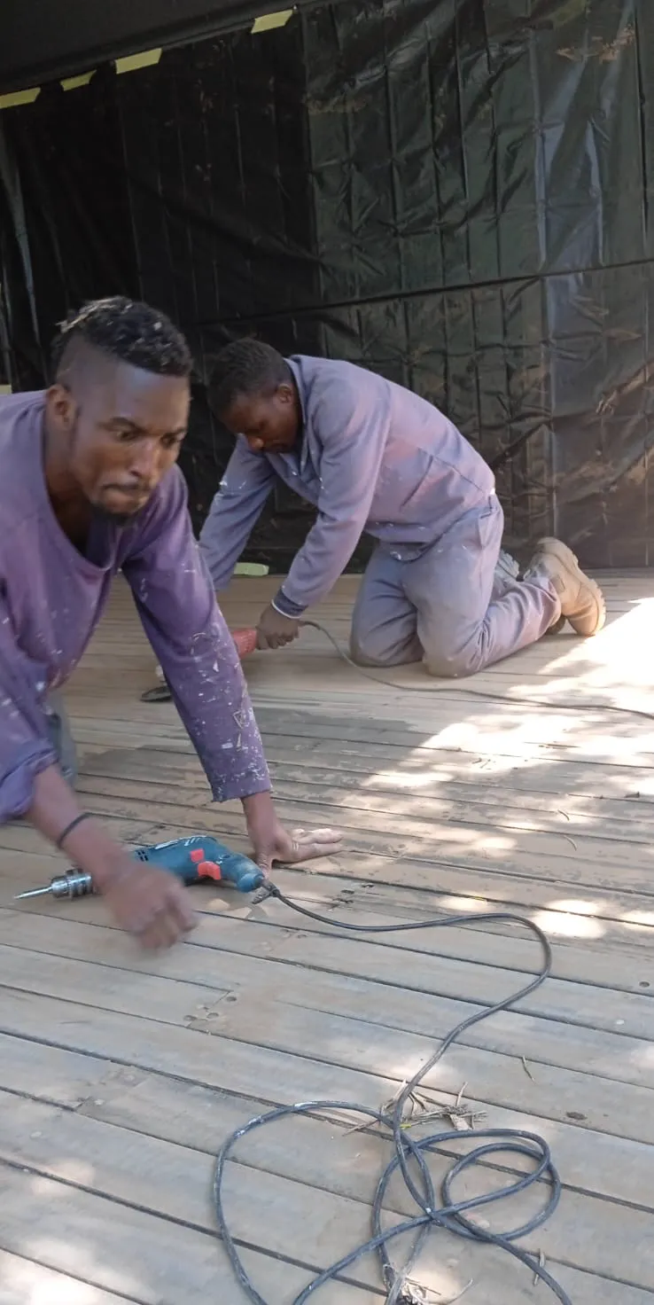 Deck restoration team sanding and refinishing timber boards