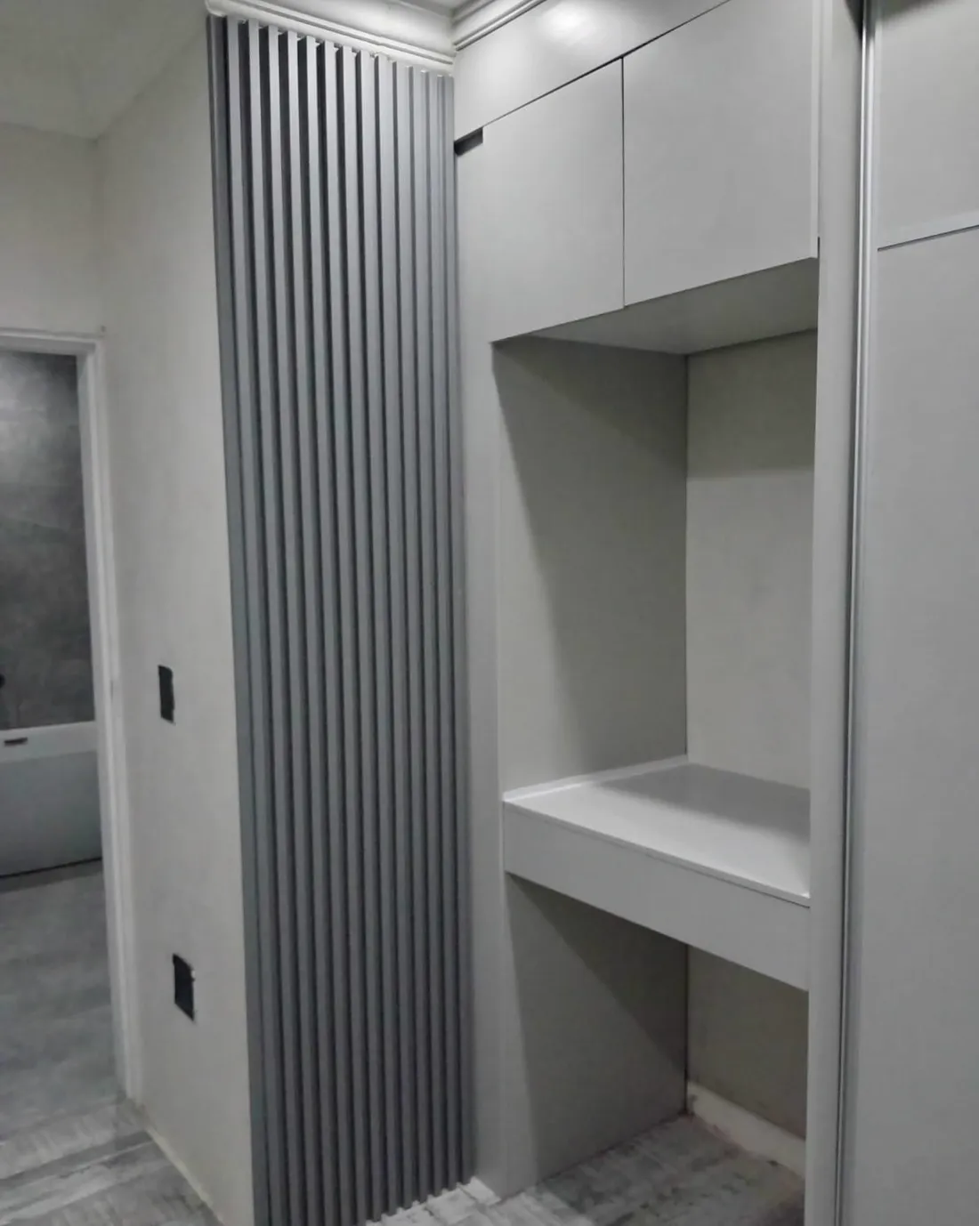 Slatted room partition beside a built-in wardrobe and shelving unit